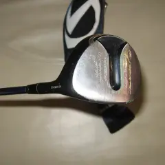 En golfklubba med en svart och silverfärgad klubbhuvud, redo att laga. En klubbhuva med ett vitt V syns i bakgrunden.