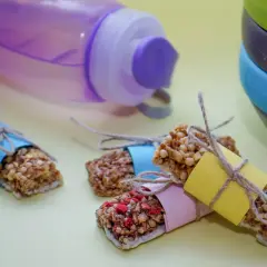 Energibars med nötter och frukt, perfekta för snabba kalorier. En lila vattenflaska och en stapel skålar i bakgrunden.