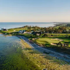 Vacker kustlinje med fina golfbanor Sverige. Grönskande fairways, sandbunkrar och en fyr vid havet.
