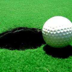 Vacker golfbana i Sverige med gröna fairways, bunkrar och vattenhinder. En flagga markerar ett golfhål med standard diameter.