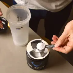 En hand skopar kreatinpulver från en burk till en shaker. Dags för en paus från kreatinuppehåll, eller kanske en ny start?