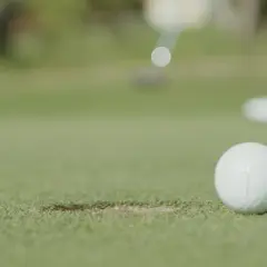 En golfspelare puttar bollen mot hålet under en handicapgrundande rond.