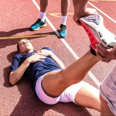 En löpare ligger på en bana medan en annan person hjälper till med stretching. Kanske en av zma biverkningar?
