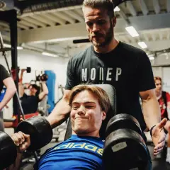 Tränare hjälper en ung man med hantlar, en riktig craze pwo-känsla i gymmet.