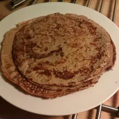 En hög med gyllenbruna proteinpannkakor på en vit tallrik. Perfekt för ett hälsosamt proteinpannkakor recept.