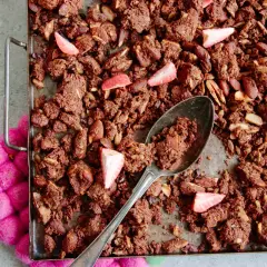 En sked tar en rejäl bit av hemgjord granola choklad med mandlar och jordgubbar.