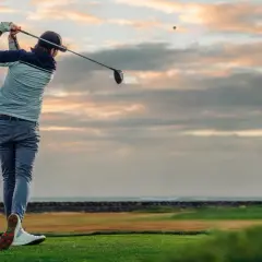 En golfare svingar klubban vid solnedgången. Ett perfekt sätt att använda sitt friskvårdsbidrag för golf.