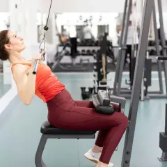 Kvinna tränar enarms latsdrag på gym.