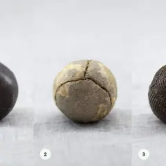 Tre gamla bollar: en mörk, en sprickig och en med rutmönster. Kanske en tidig guttaperka boll?