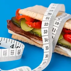 En mätsticka lindad runt en proteinrik smörgås, en visuell representation av att protein kan hjälpa till att gå upp i vikt.