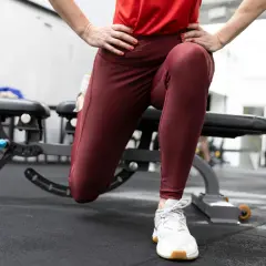 En person utför split squats i ett gym. En boxningssäck syns i bakgrunden.