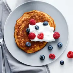 En gyllene pannkaka toppad med grädde och färska bär. En perfekt start på dagen med en nyttig frukost.