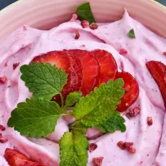 Keso glass med jordgubbar och mynta. En rosa, krämig dessert med färska jordgubbskivor och torkade bär.