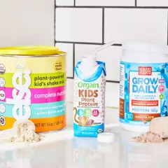Tre olika produkter med proteinpulver för barn: en burk med vaniljsmak, en färdigblandad chokladshake och en burk med chokladsmak.