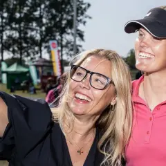 Två glada kvinnor tar en selfie vid Helsingborg Open. En kvinna med glasögon och en golfare i rosa tröja ler mot kameran.
