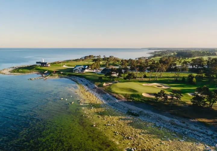Vacker kustlinje med fina golfbanor Sverige. Grönskande fairways, sandbunkrar och en fyr vid havet.