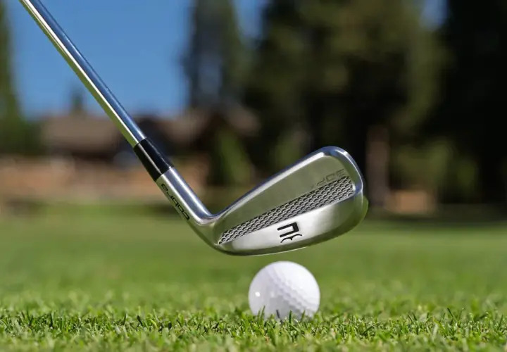 En golfklubba av märket Cobra närmar sig en golfboll på en grön gräsmatta. Frågan om hur långa golfklubbor ska man ha är central för spelet.