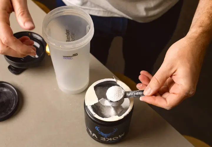 En hand skopar kreatinpulver från en burk till en shaker. Dags för en paus från kreatinuppehåll, eller kanske en ny start?
