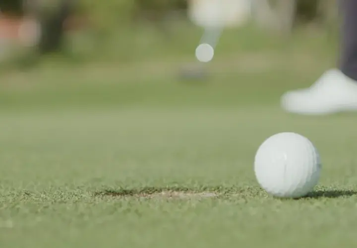 En golfspelare puttar bollen mot hålet under en handicapgrundande rond.