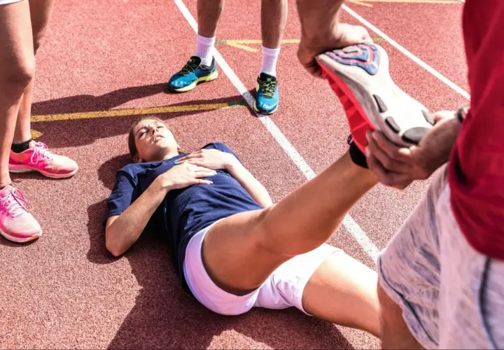 En löpare ligger på en bana medan en annan person hjälper till med stretching. Kanske en av zma biverkningar?