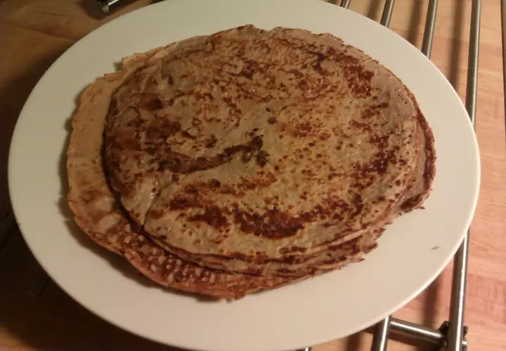 En hög med gyllenbruna proteinpannkakor på en vit tallrik. Perfekt för ett hälsosamt proteinpannkakor recept.