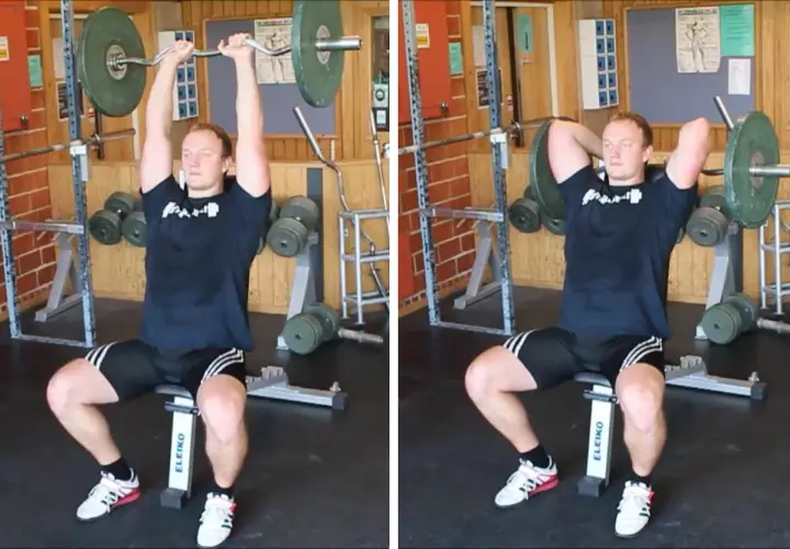Man utför french press i gym. Han sitter på en bänk och håller en skivstång över huvudet.