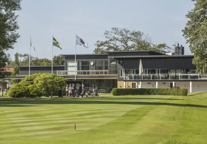 En golfklubb i Sverige med en modern byggnad, flaggor och välklippta fairways. Här kan man höra många golftermer.