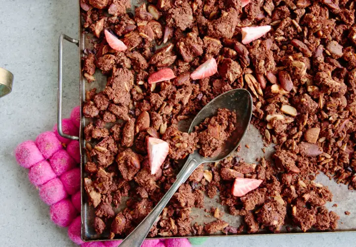 En sked tar en rejäl bit av hemgjord granola choklad med mandlar och jordgubbar.