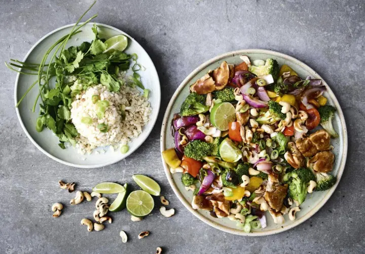 Två tallrikar med mat. En med ris, koriander och lime. Den andra med kyckling, broccoli, paprika, lök, cashewnötter och lime – en fest av nyttiga råvaror.