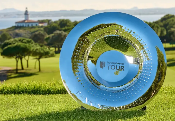 En glänsande pokal på en golfbana, med en fyr med hav i bakgrunden. Denna trofé symboliserar framgången i en **challenge tour**.