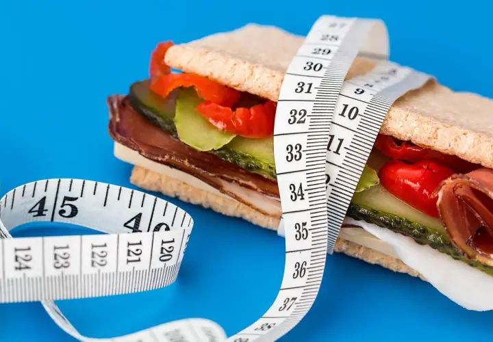 En mätsticka lindad runt en proteinrik smörgås, en visuell representation av att protein kan hjälpa till att gå upp i vikt.