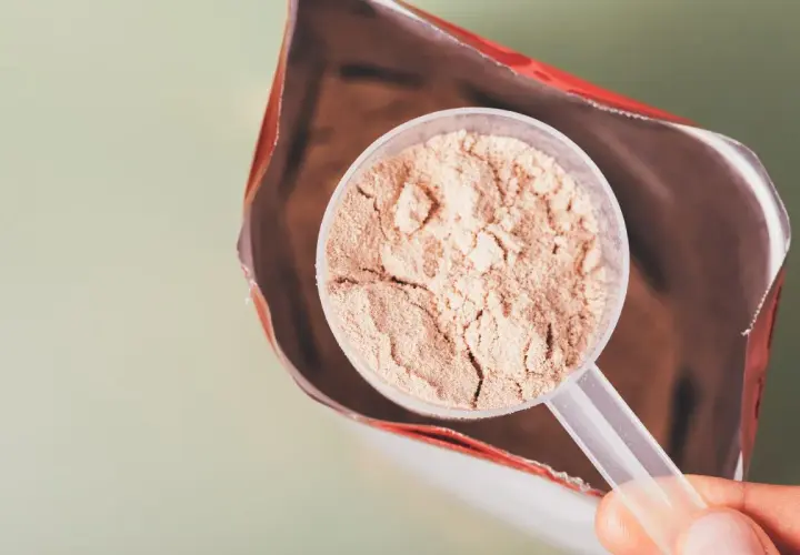 En skopa proteinpulver tas ur en påse. Frågan är om man går upp i vikt av proteinpulver.