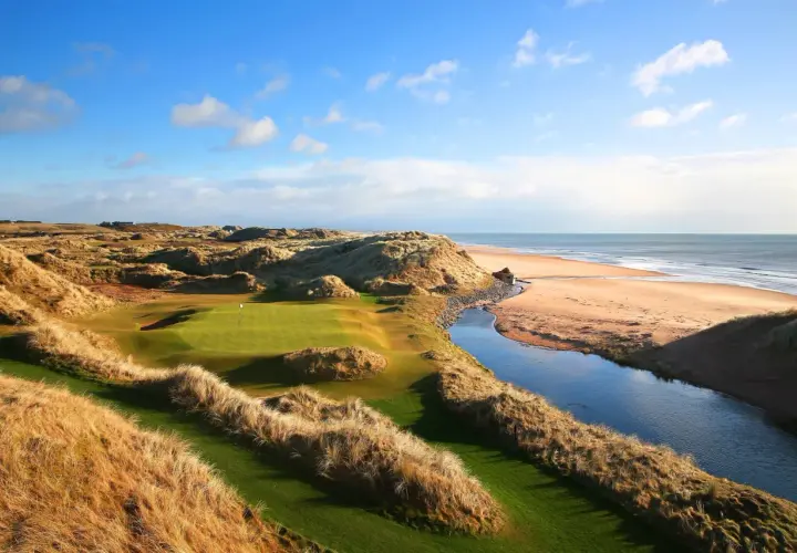 En golfbana vid havet, med böljande sanddyner och en porlande bäck. En vy som påminner om golf historia.