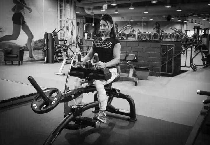 Kvinna tränar sittande vadpress på gym.