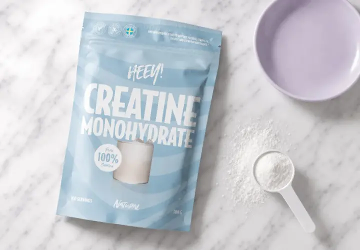 Påse med HEEY! Kreatin Monohydrat, perfekt för kreatin laddning. Pulver och skopa syns bredvid.