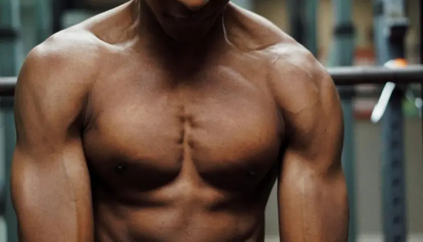 En vältränad man med synliga muskler i bröst och armar. Hans kropp visar resultatet av hårt arbete och ett intag av långsamt protein för muskeluppbyggnad.