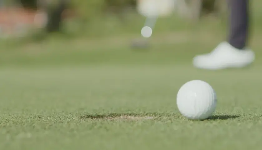 En golfspelare puttar bollen mot hålet under en handicapgrundande rond.