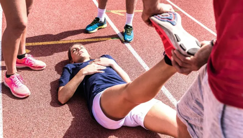 En löpare ligger på en bana medan en annan person hjälper till med stretching. Kanske en av zma biverkningar?
