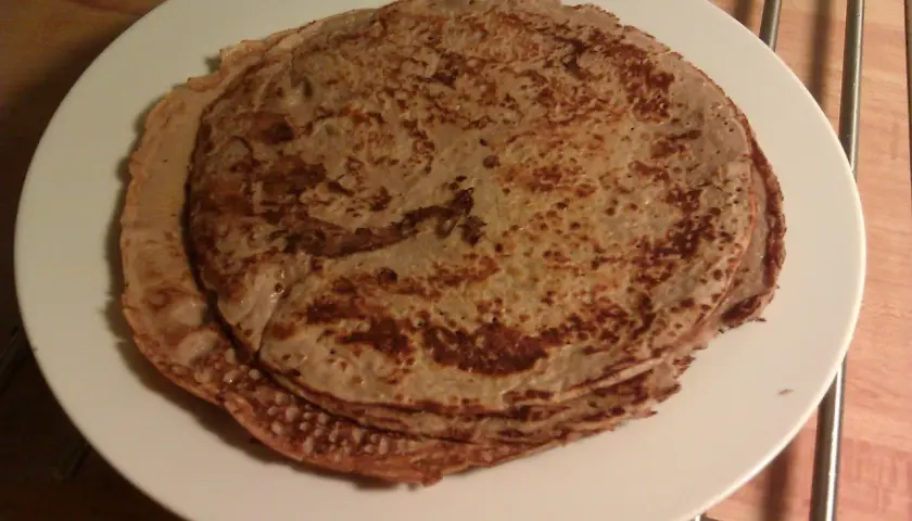 En hög med gyllenbruna proteinpannkakor på en vit tallrik. Perfekt för ett hälsosamt proteinpannkakor recept.