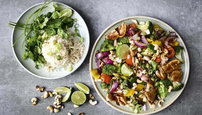 Två tallrikar med mat. En med ris, koriander och lime. Den andra med kyckling, broccoli, paprika, lök, cashewnötter och lime – en fest av nyttiga råvaror.