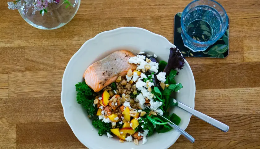 Laxskål med krispig grönkål, frukt, nötter och ost. En hälsosam måltid med cirka 30g protein.