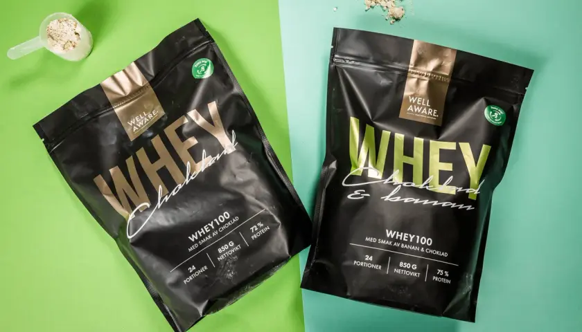 Två påsar Well Aware Whey100, en med chokladsmak och en med banan & choklad. Jämför whey 100 vs 80 för din träning.