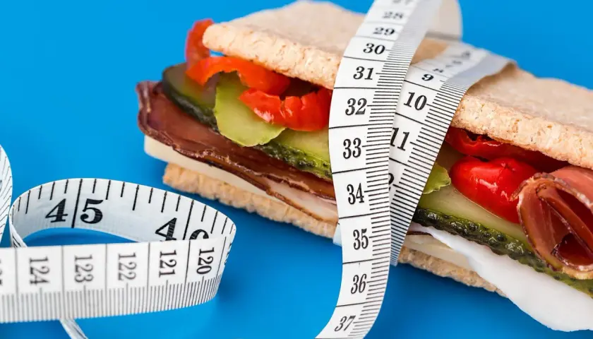 En mätsticka lindad runt en proteinrik smörgås, en visuell representation av att protein kan hjälpa till att gå upp i vikt.