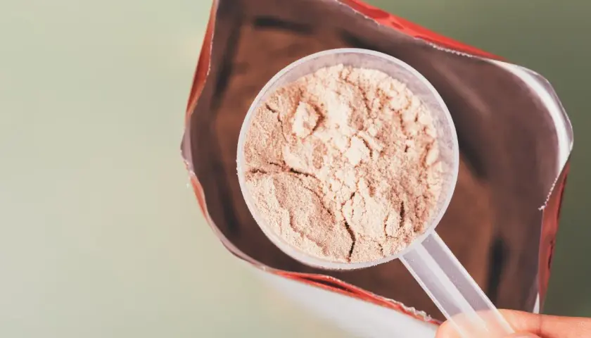 En skopa proteinpulver tas ur en påse. Frågan är om man går upp i vikt av proteinpulver.