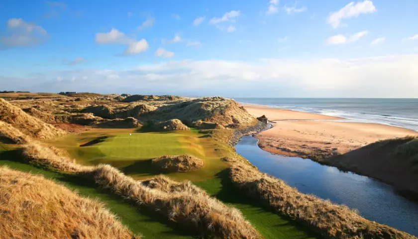 En golfbana vid havet, med böljande sanddyner och en porlande bäck. En vy som påminner om golf historia.