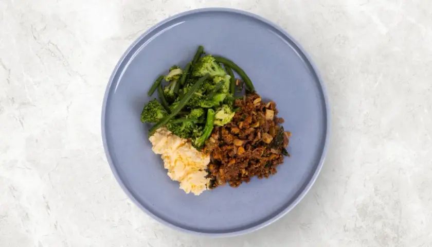 En tallrik med mat utan kolhydrater och socker: äggröra, broccoli med gröna bönor och köttfärs.