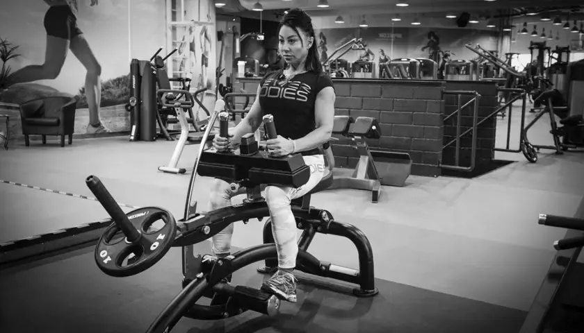 Kvinna tränar sittande vadpress på gym.