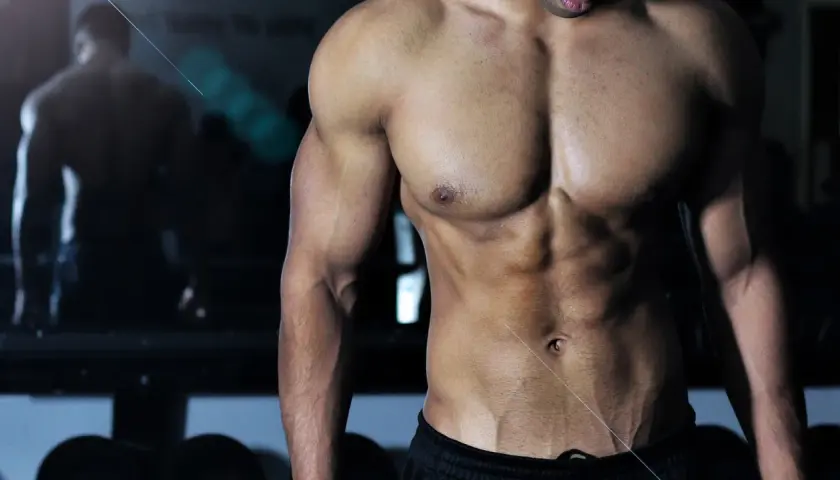Muskulös man i gym, med fokus på magmuskler och armar. Bra inspiration för viktnedgång tips och träning.