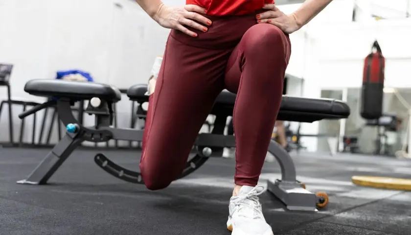 En person utför split squats i ett gym. En boxningssäck syns i bakgrunden.
