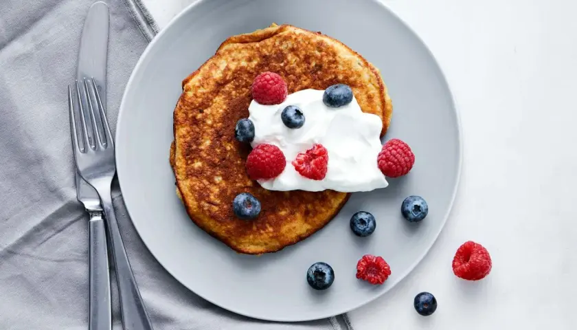 En gyllene pannkaka toppad med grädde och färska bär. En perfekt start på dagen med en nyttig frukost.